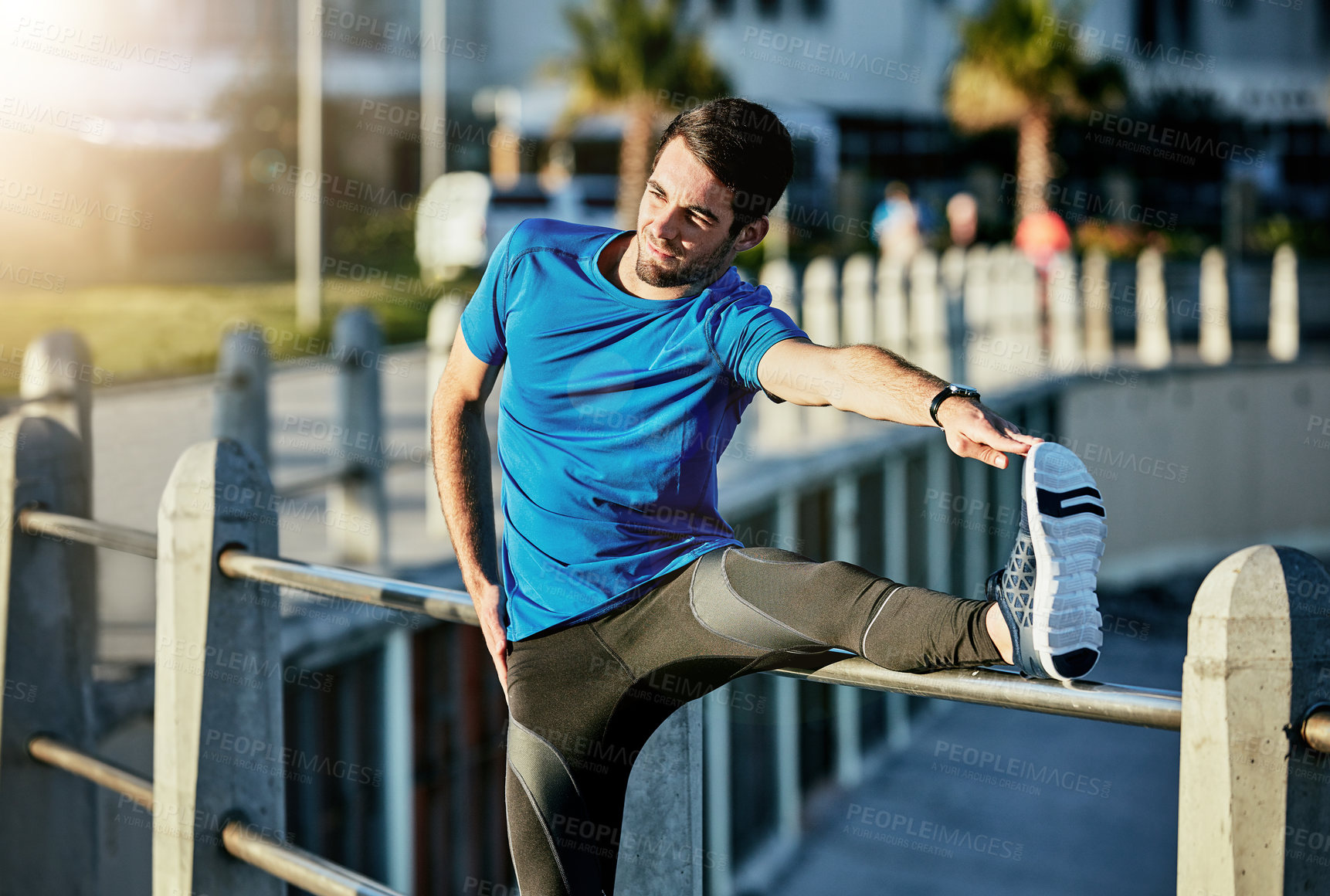 Buy stock photo Shot of a young man stretching outside before his run