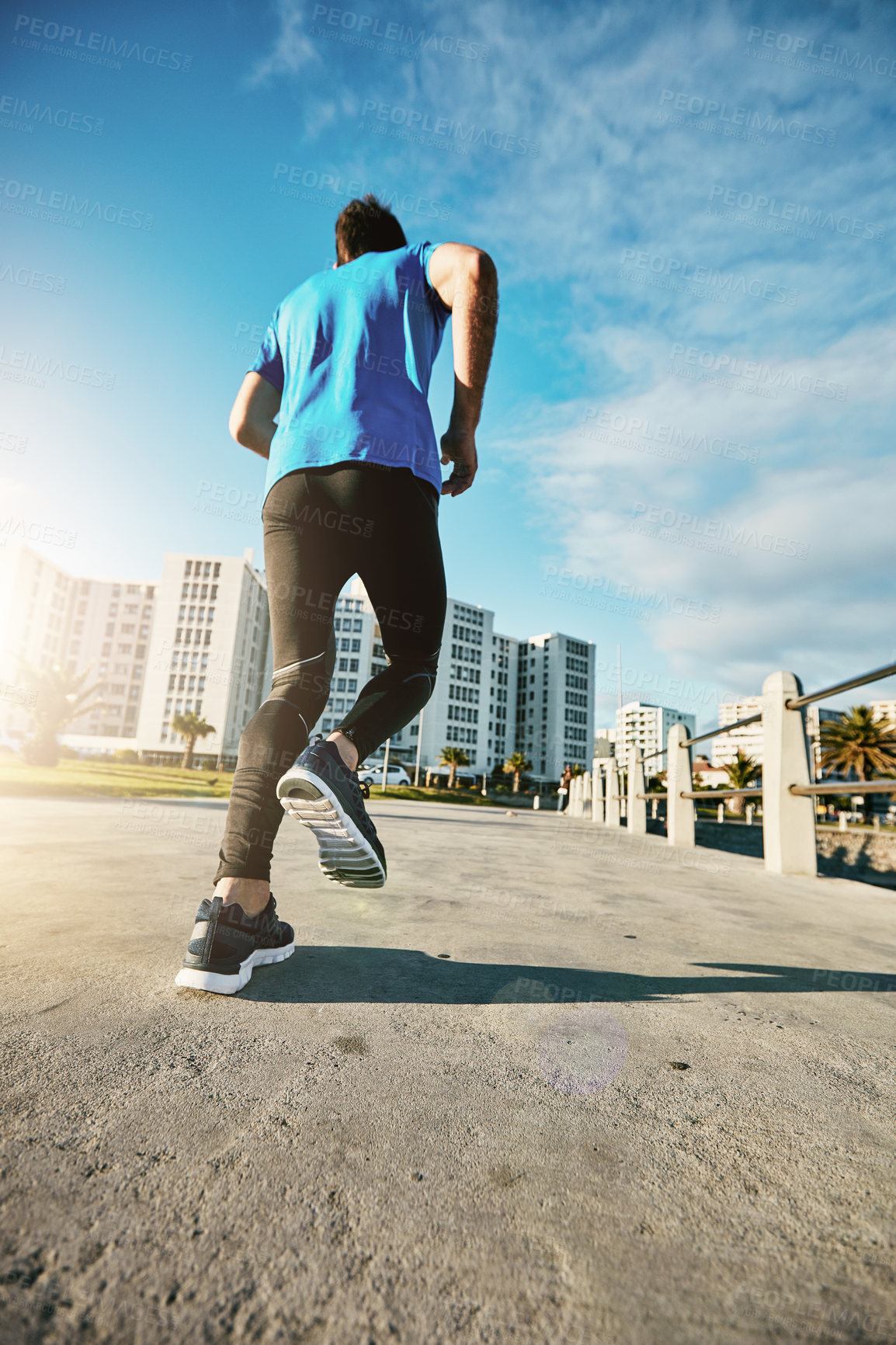 Buy stock photo Rearview shot of a sporty young man out for a run