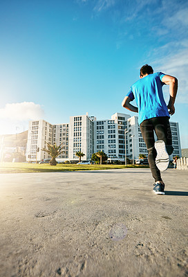 Buy stock photo Rearview shot of a sporty young man out for a run