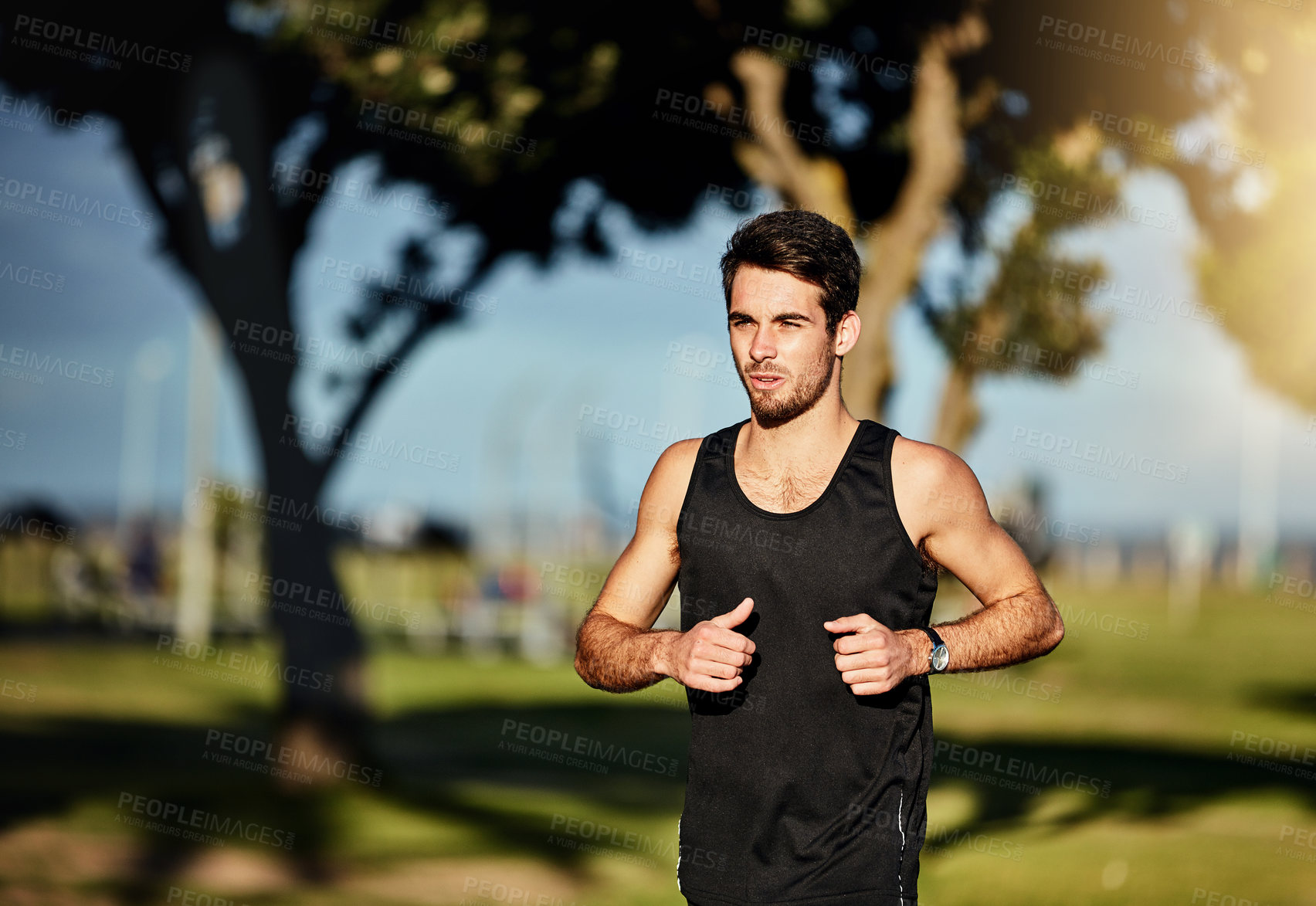 Buy stock photo Shot of a young man out for a jog in a park