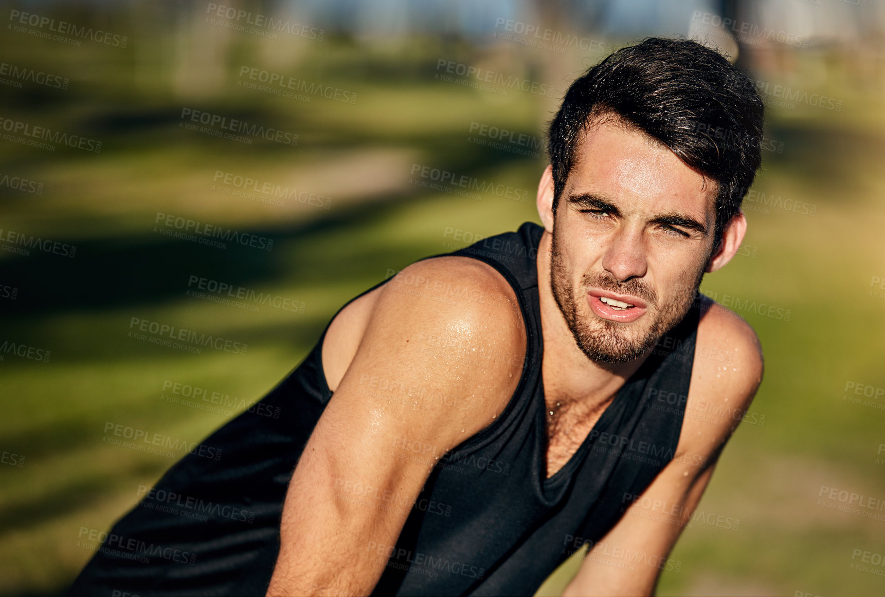 Buy stock photo Shot of a young jogger resting while out for a run in a park