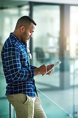 Buy stock photo Cropped shot of a handsome young businessman using his tablet in the office