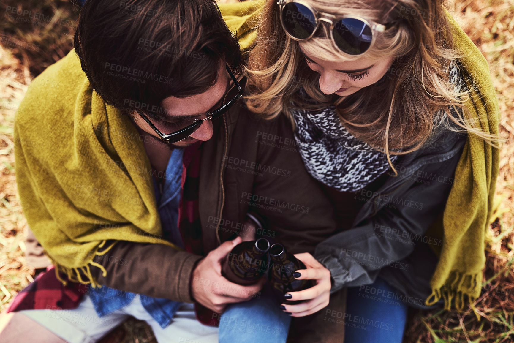 Buy stock photo Above, couple and toast with beer bottle on picnic for fun, love and bonding in outdoor. Relationship, people and happy with alcohol on holiday for adventure or travel for support, trust and break