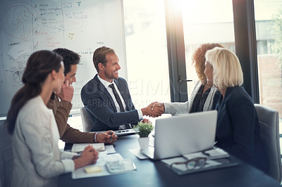 Buy stock photo Shot of a two corporate colleagues shaking hands during a boardroom meeting