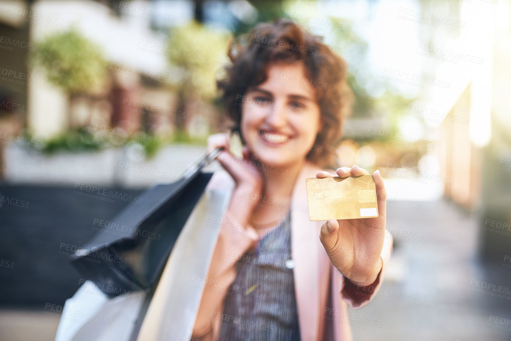 Buy stock photo Shot of a woman holding up her credit card while out shopping