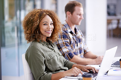 Buy stock photo Portrait of a young designer working on a laptop with her colleague in the background