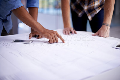 Buy stock photo Closeup shot of two young architects working on blueprints in an office