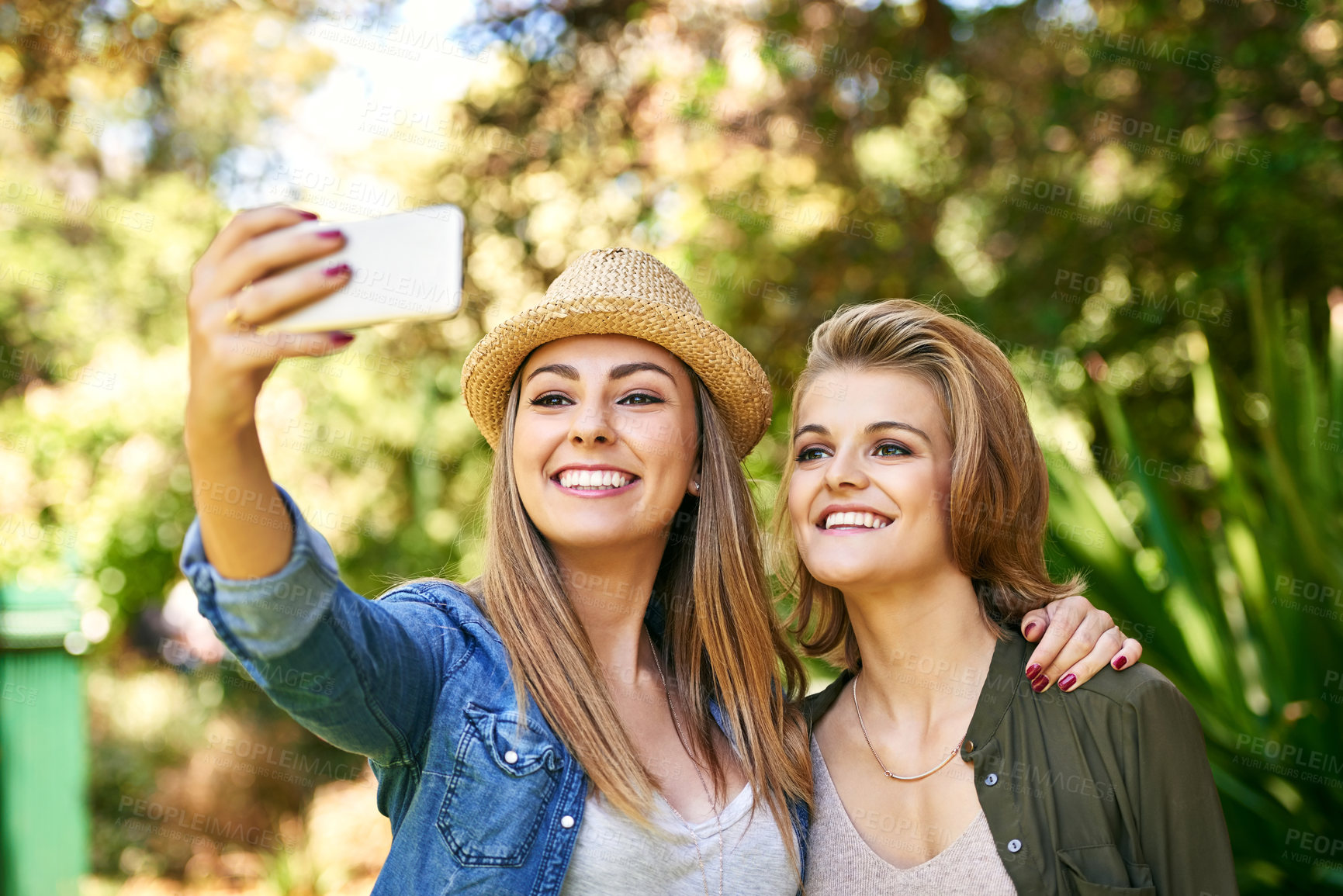 Buy stock photo Cropped shot of two attractive young women taking selfies outside