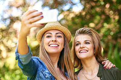 Buy stock photo Cropped shot of two attractive young women taking selfies outside