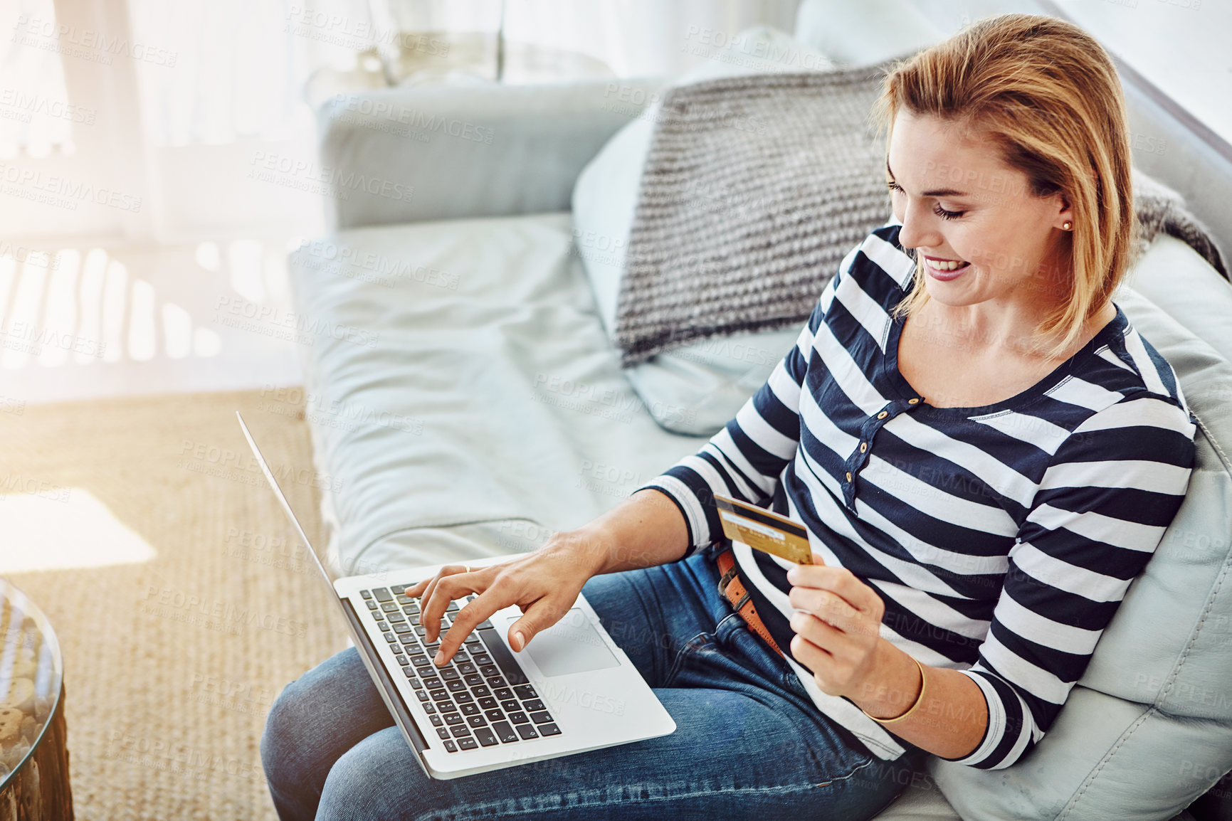 Buy stock photo High angle shot of an attractive young woman shopping online from the comfort of home