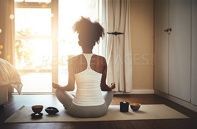 Buy stock photo Rearview shot of a sporty young woman practicing yoga indoors