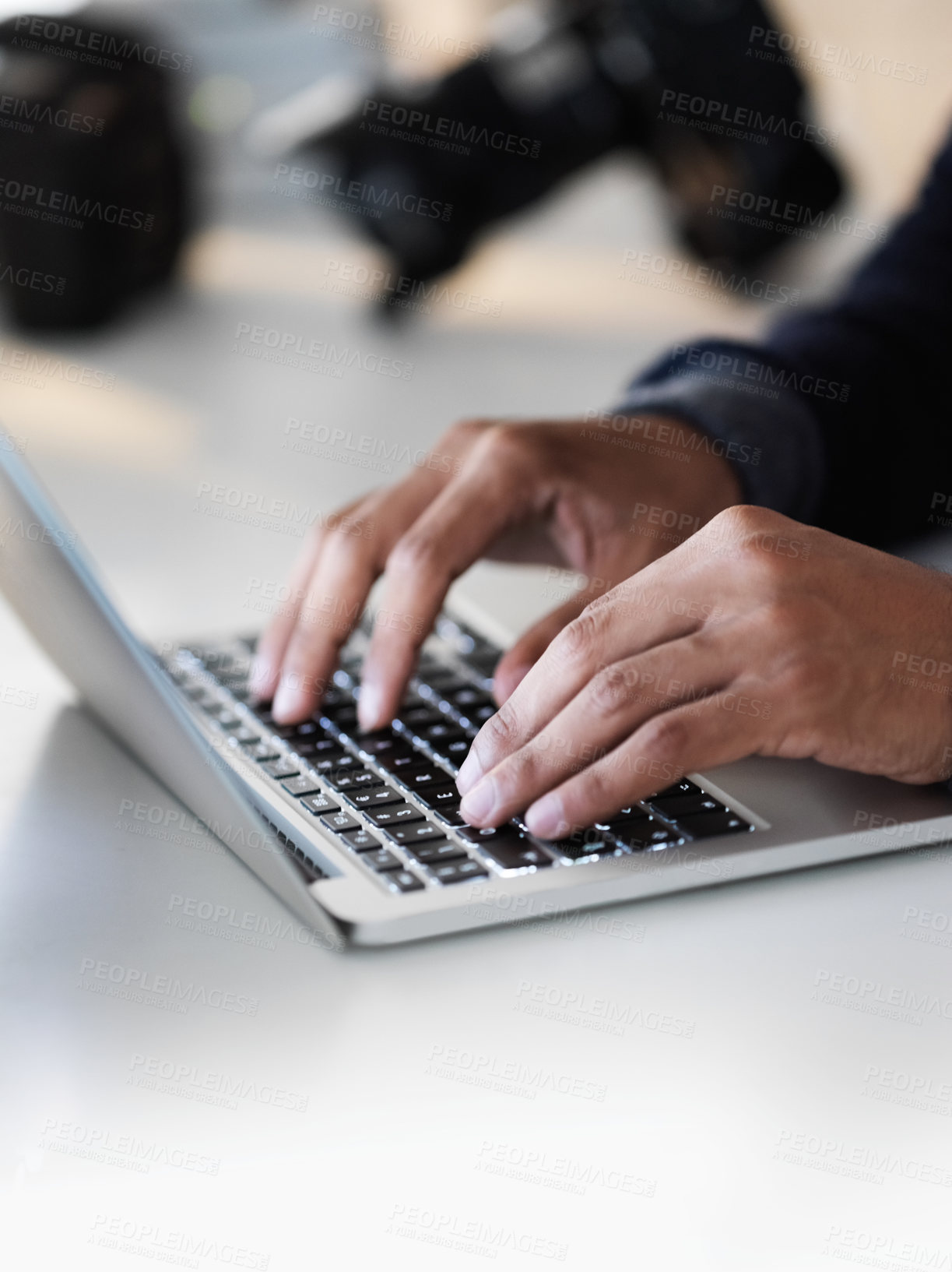 Buy stock photo Cropped closeup shot of an unrecognizable photographer sitting at a table using a laptop