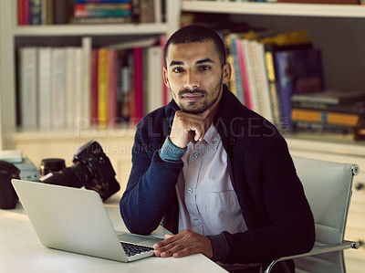 Buy stock photo Portrait of a focused young photographer working on a laptop in his home office in the early evening