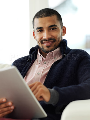 Buy stock photo Portrait of a smiling young man working at home on a digital tablet