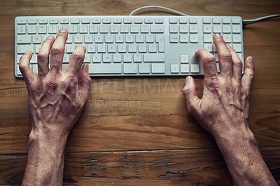Buy stock photo High angle shot of an unidentifiable man typing on a computer keyboard at night