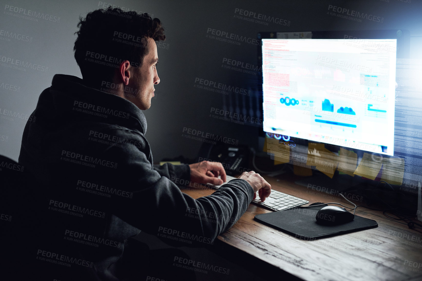 Buy stock photo Rearview shot of a young programmer working on his computer late at night