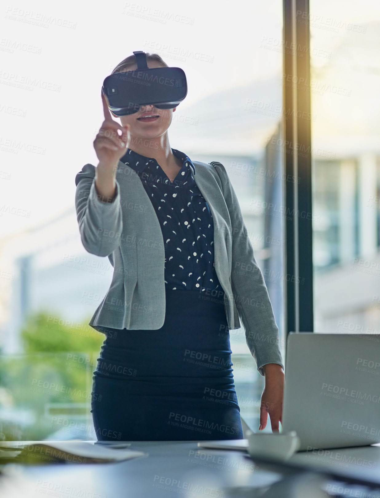Buy stock photo Shot of a young businesswoman wearing a virtual reality headset at work