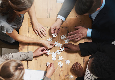 Buy stock photo High angle shot of a group of businesspeople building a puzzle together in an office