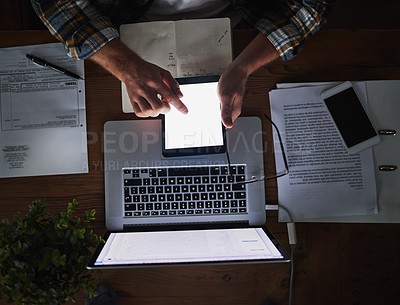 Buy stock photo Laptop and tablet in the hands of a man working late at night in the office from above. Deadline and overtime at a desk with technology and paper work. Sending an email reading or typing a report