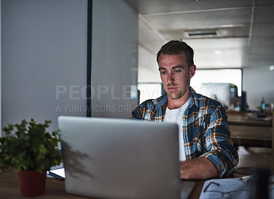 Buy stock photo Shot of a focussed young programmer using his laptop in the office
