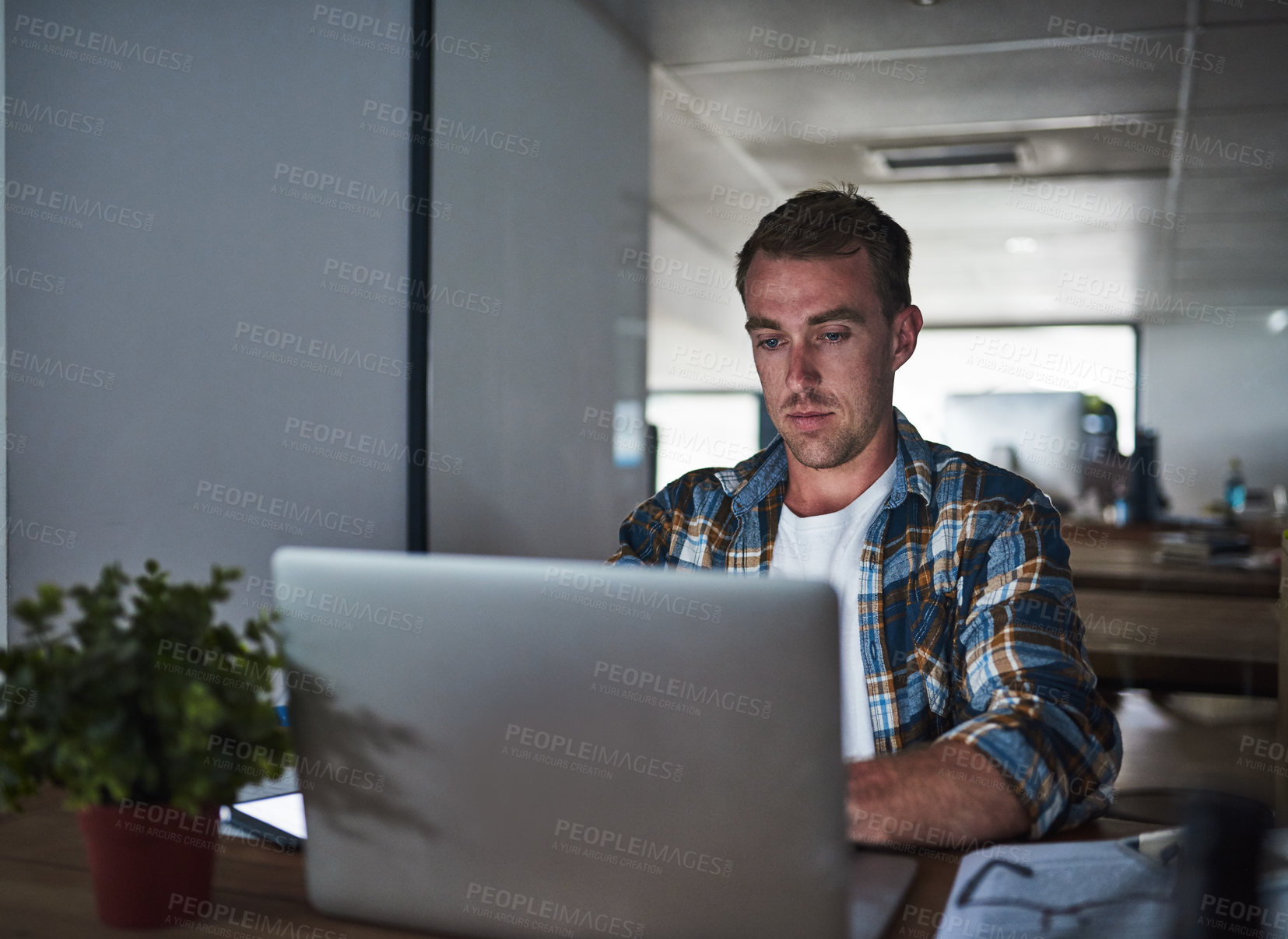 Buy stock photo Shot of a focussed young programmer using his laptop in the office