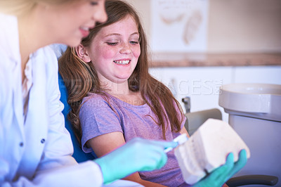 Buy stock photo Cropped shot of a female dentist teaching her young patient how to brush her teeth