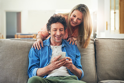 Buy stock photo Shot of a happy mature couple using a mobile phone together at home