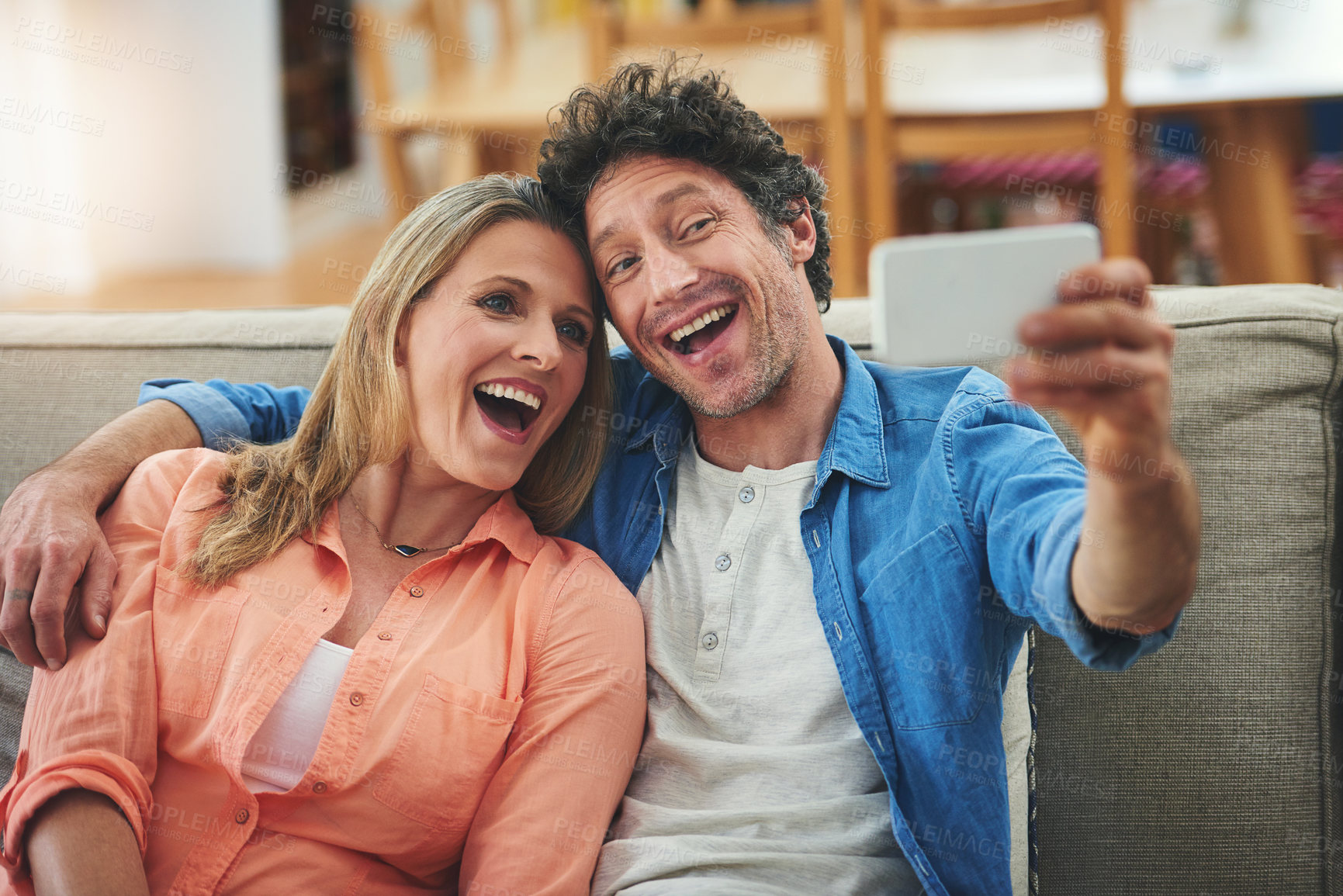 Buy stock photo Couple, selfie and couch in home, smile and excited for memory with bonding for love with connection. People, man and woman with embrace for care, happy and profile picture on app for social network