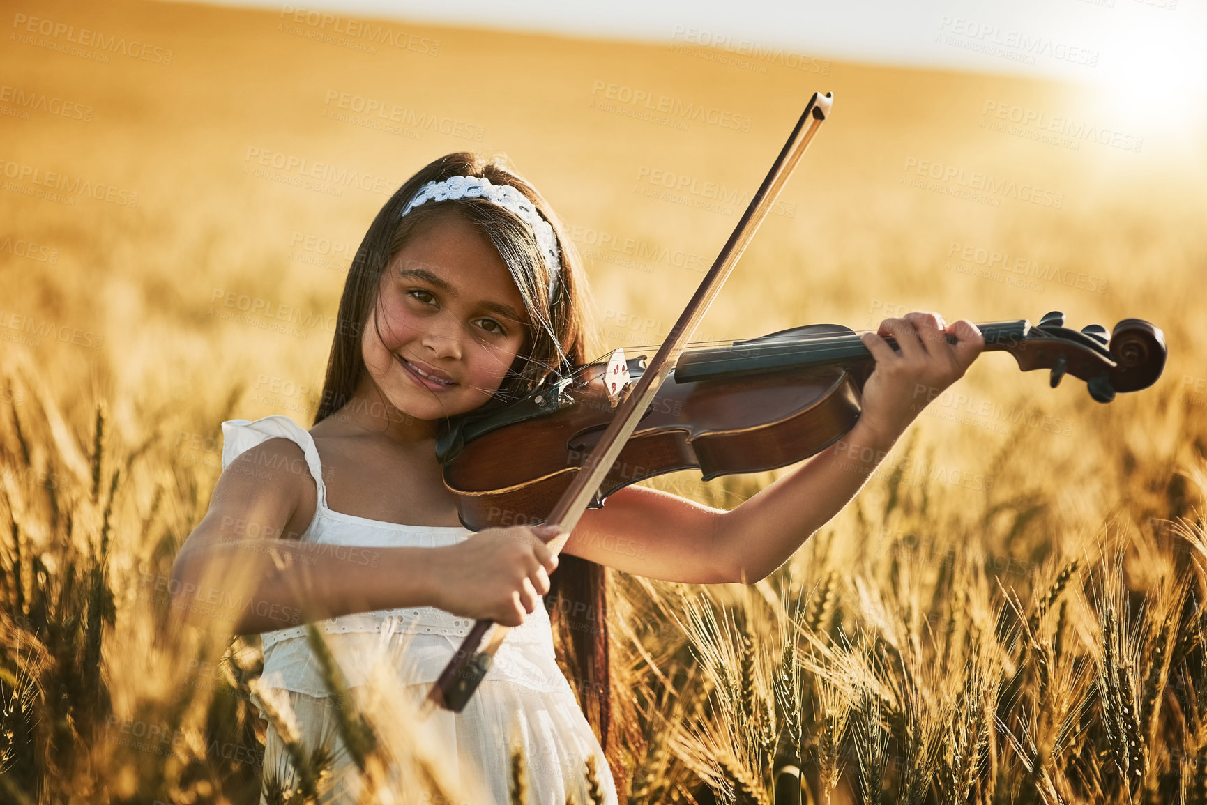 Buy stock photo Portrait, girl child and playing violin in cornfield for concert performance, talent and outdoor practice. Young kid, smile and string instrument for music in nature for art, development and growth