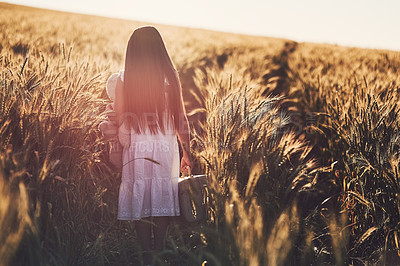 Buy stock photo Girl, walking and back in corn field in nature, rural area and sustainable farming land with child. Suitcase, peaceful and independent exploration in countryside, agriculture and outside on weekend 