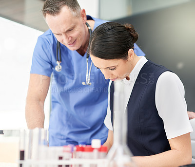 Buy stock photo Shot of two doctors examining test results together in the lab