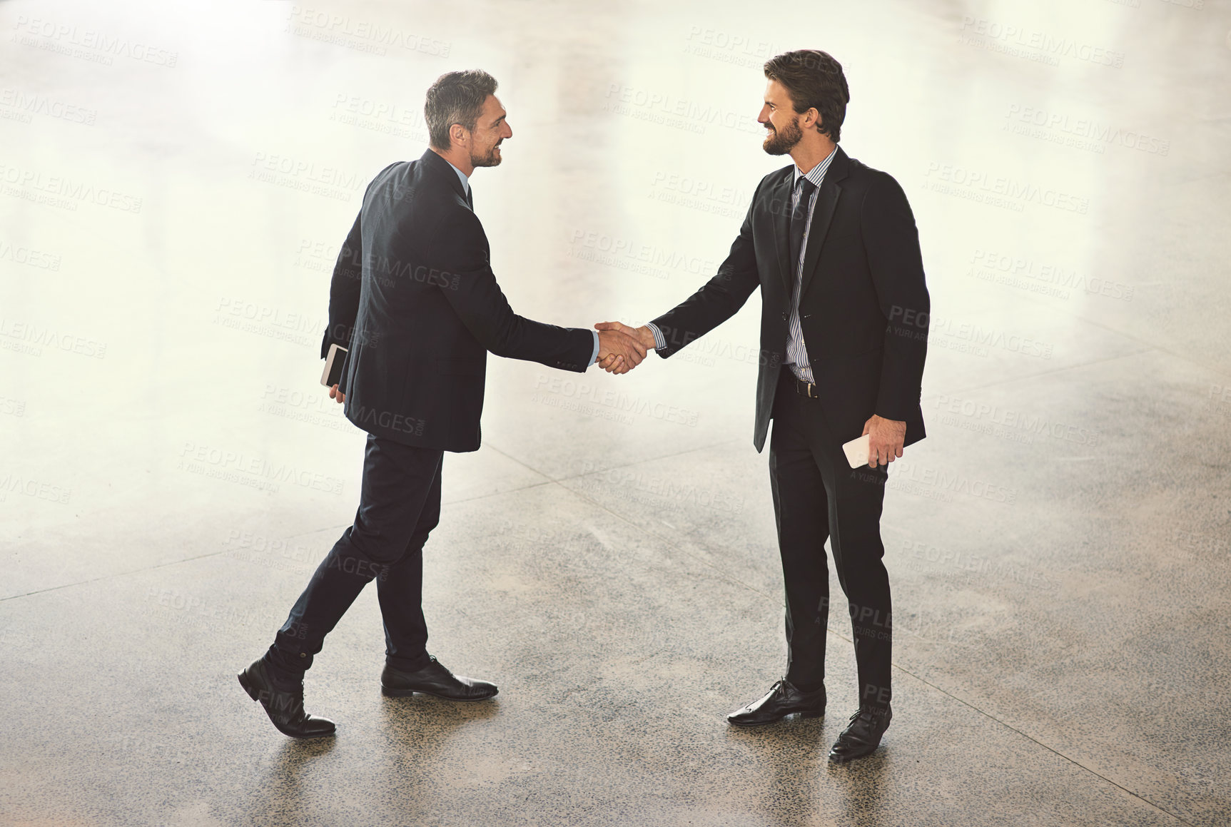 Buy stock photo High angle shot of two businessmen shaking hands in an office lobby