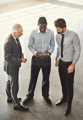 Buy stock photo High angle shot of a group of businessmen talking together while standing in an office lobby