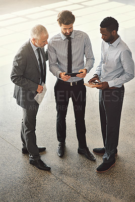 Buy stock photo High angle shot of a group of businessmen talking together while standing in an office lobby