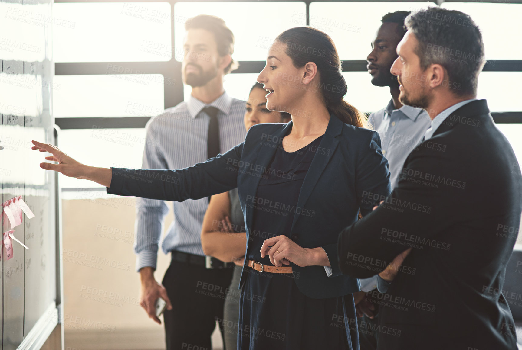 Buy stock photo Shot of young businesspeople discussing ideas on a whiteboard during a meeting in an office