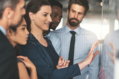 Buy stock photo Shot of young businesspeople discussing ideas on a whiteboard during a meeting in an office
