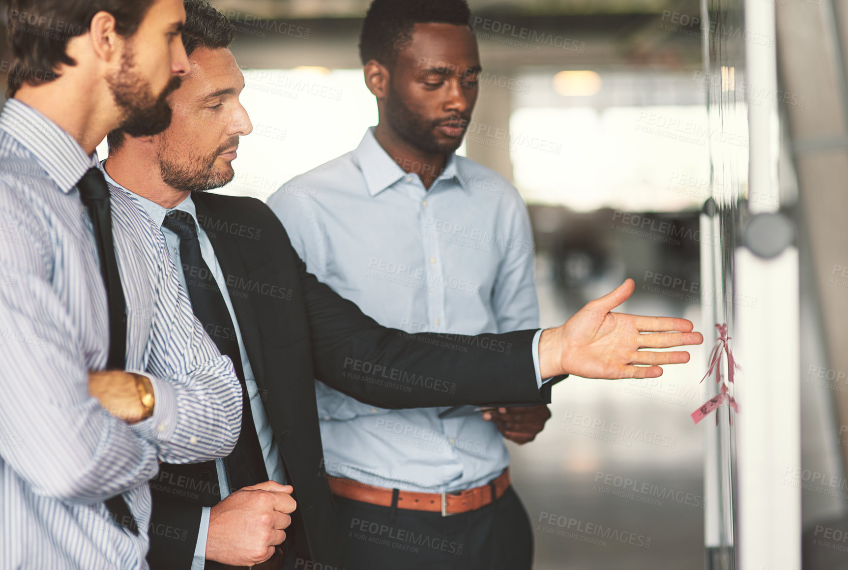 Buy stock photo Shot of young businesspeople discussing ideas on a whiteboard during a meeting in an office