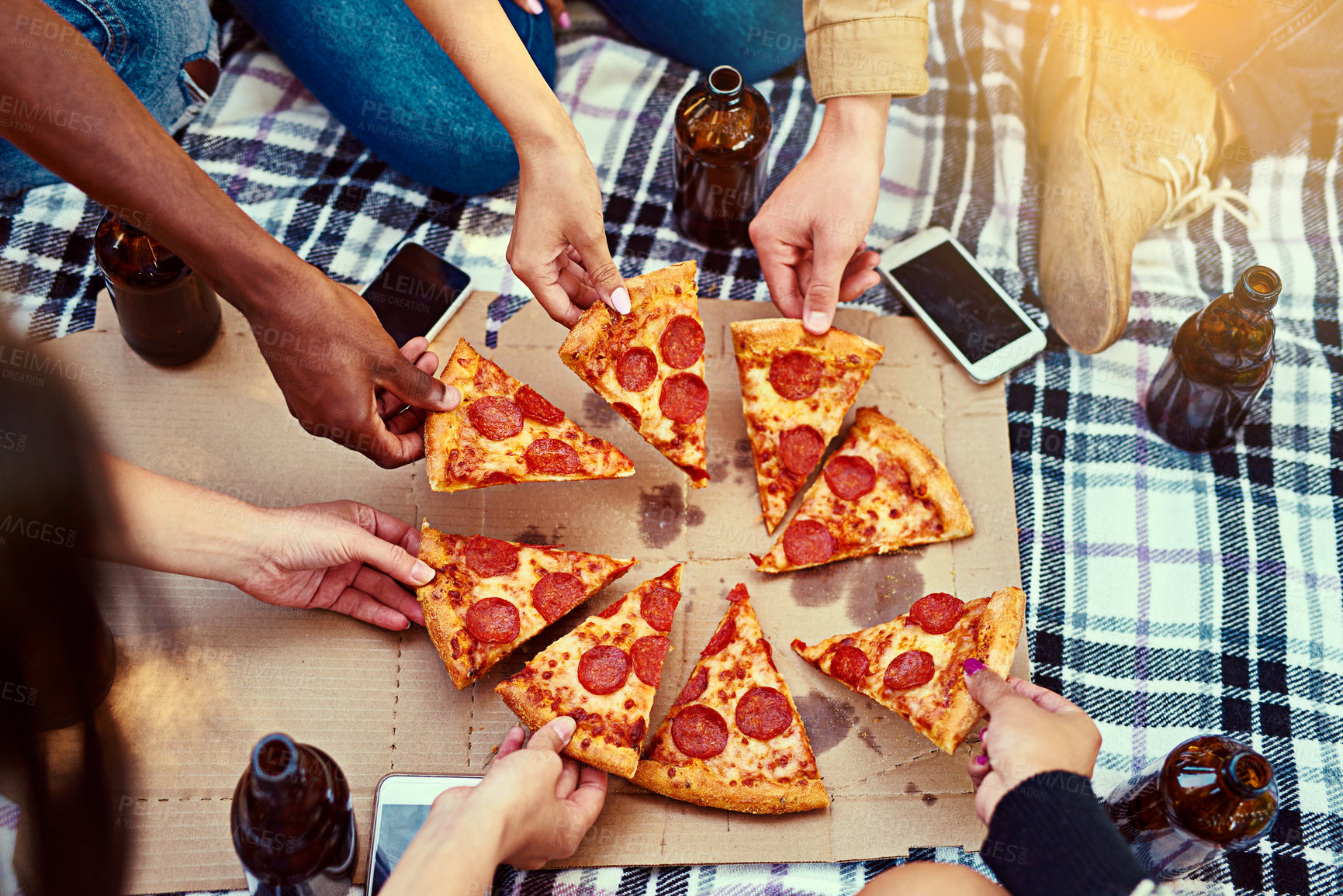 Buy stock photo Cropped shot of a group of friends eating pizza while having a picnic