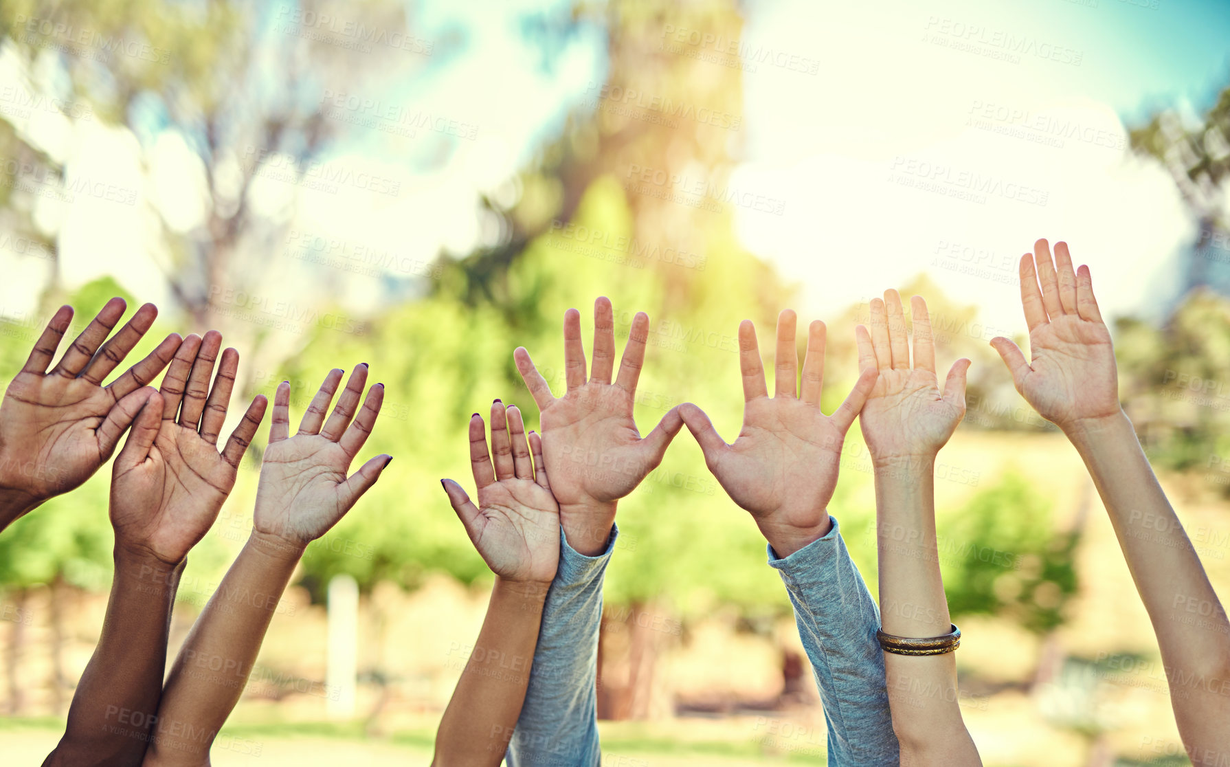 Buy stock photo Cropped shot of a diverse group of people raising their hands in the air