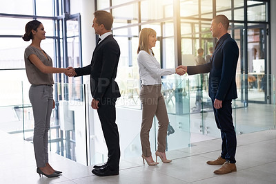 Buy stock photo Shot of a group of businesspeople shaking hands in an office