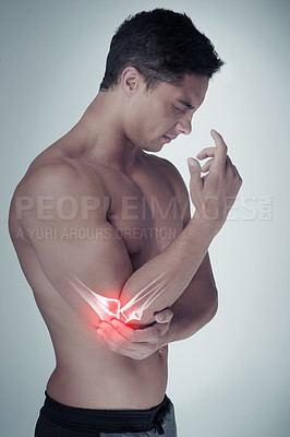 Buy stock photo Studio shot of an athletic young man holding his elbow in pain against a grey background