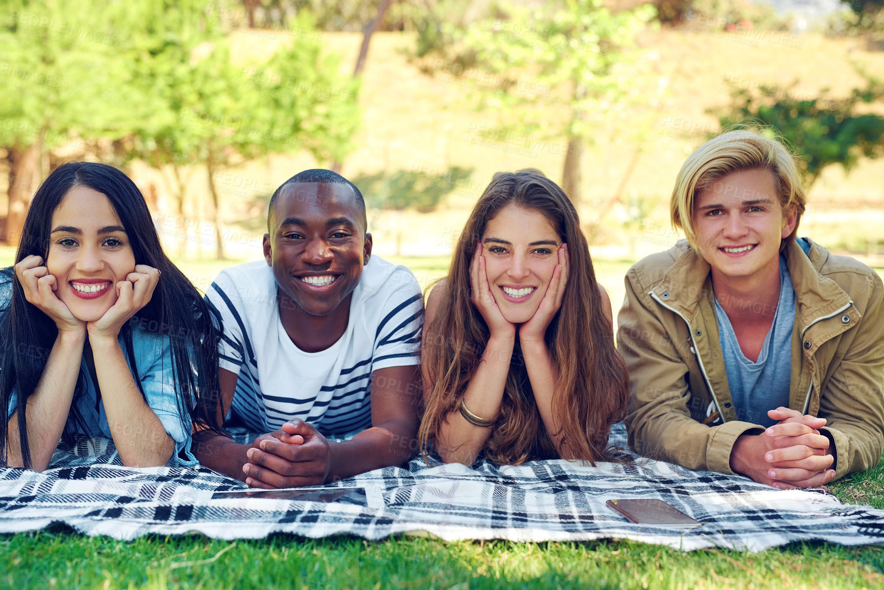 Buy stock photo Friends, group and portrait with blanket at park for solidarity with diversity, break and relax on grass field. Men, women and people at picnic, happy or bonding with connection on lawn at college