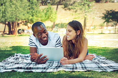 Buy stock photo Happy couple, relax and students on tablet at park on blanket with smile for meme, funny video or streaming. Man, women or people on break with social media or online subscription for movie on lawn