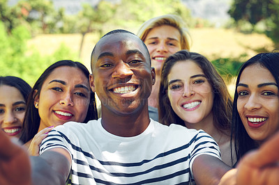 Buy stock photo Shot of a group of young friends taking a selfie together outdoors