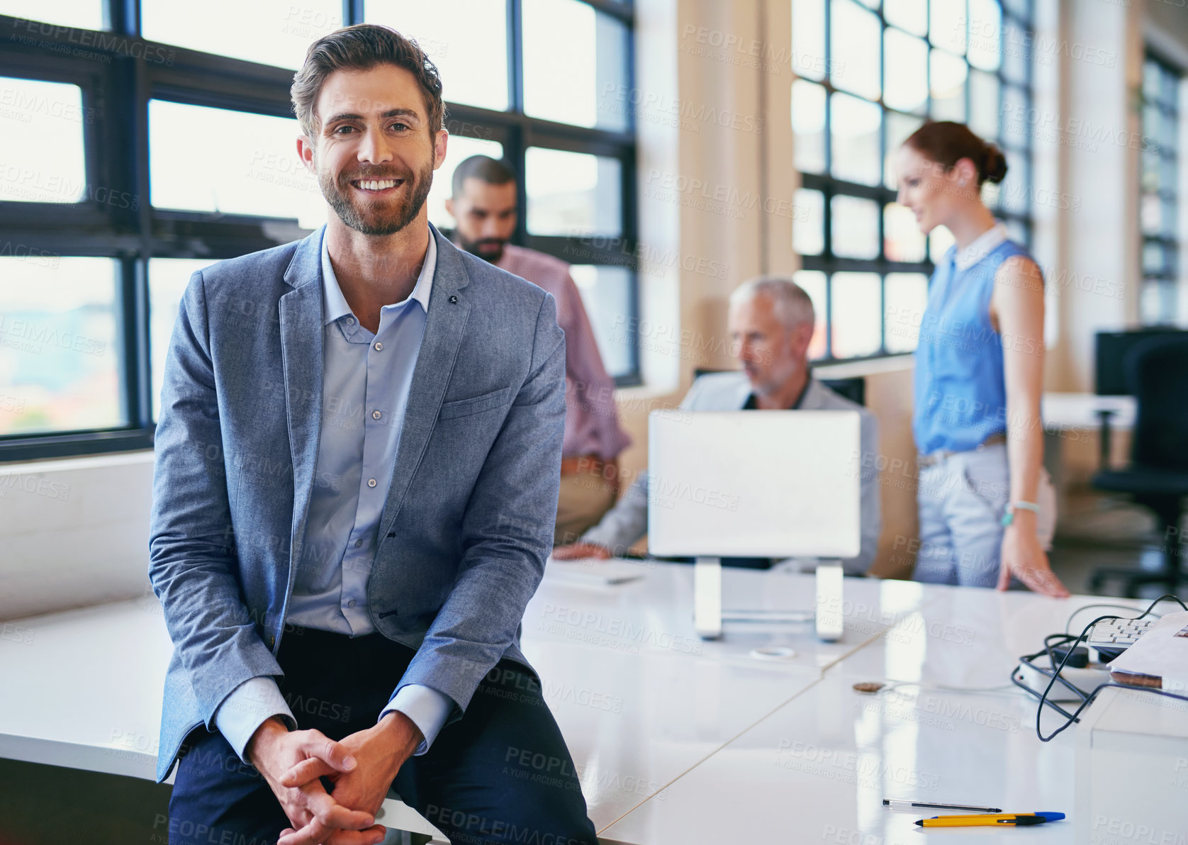Buy stock photo Portrait of a confident businessman posing in the office with his colleagues in the background