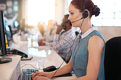 Buy stock photo Shot of a happy call center agent working at her computer in the office