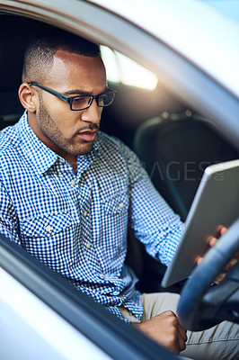 Buy stock photo Cropped shot of a young businessman using a digital tablet while driving a car