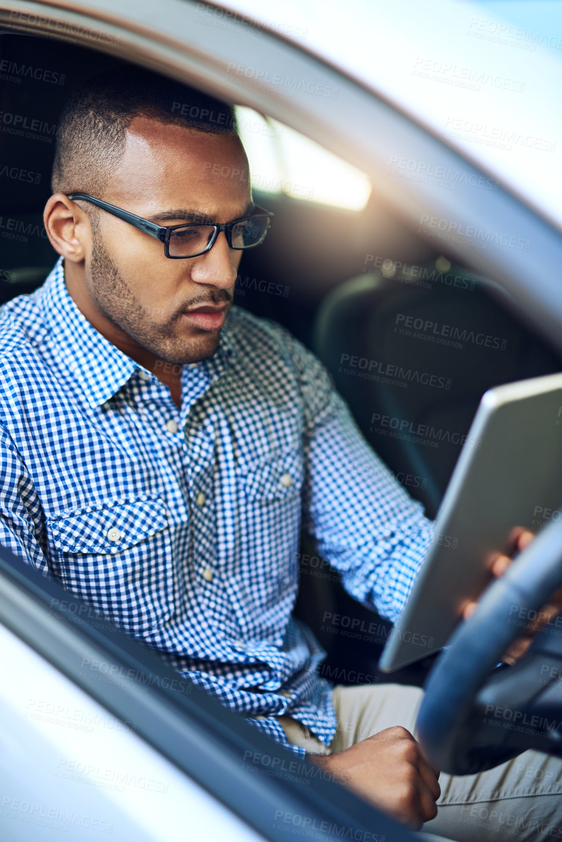 Buy stock photo Cropped shot of a young businessman using a digital tablet while driving a car