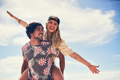 Buy stock photo Portrait of an attractive young woman getting a piggyback from her boyfriend on the beach