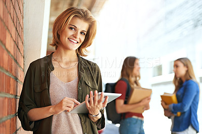 Buy stock photo Portrait of a smiling female university student standing on campus using a digital tablet with friends in the background